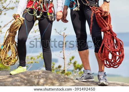 a couple of climbers with ropes on a cliff top. mountain climbing equipment