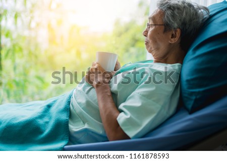 asian senior patient man take a rest with hot tea on hospital bed health ideas concept