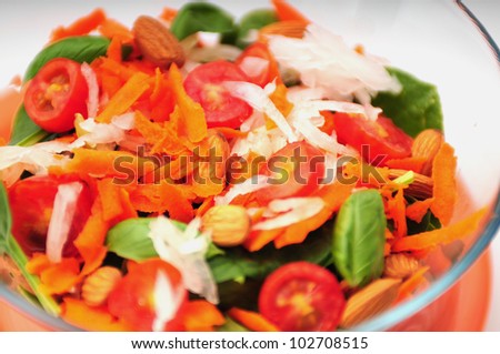 A healthy vegan salad with tomatoes, lettuce, spinach almonds and carrots