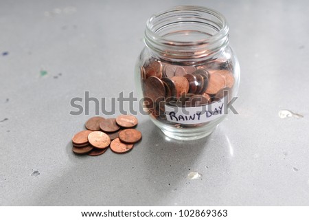 A jar of pennies for a rainy day on a decorative concrete background