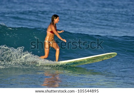 Beautiful young woman surfing a wave in the  ocean