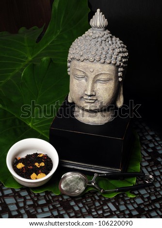 Black tea leaves with Buddha statue and tea infuser or strainer