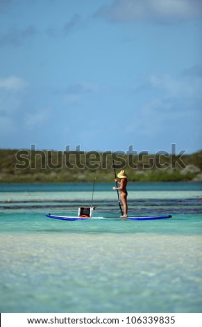 young woman fishing on paddle board in tropical scenic ocean waters