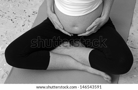 pregnant woman practicing prenatal yoga while holding belly