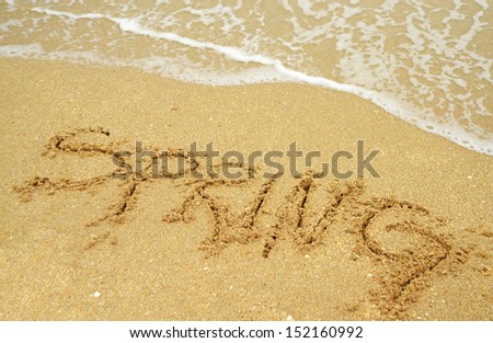 A warm tropical beach for spring break concept and spring written in the sand