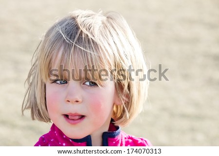 Little girl with wary look and tongue sticking out
