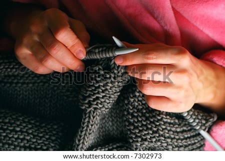 Young woman hands knitting a grey pullover
