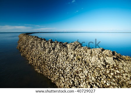 Long seawall running out into the ocean and under deep blue sky