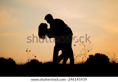 Silhouettes of hugging couple against the sunset sky. Vintage photo.
