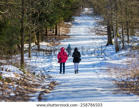 people walking in winter forest with child
