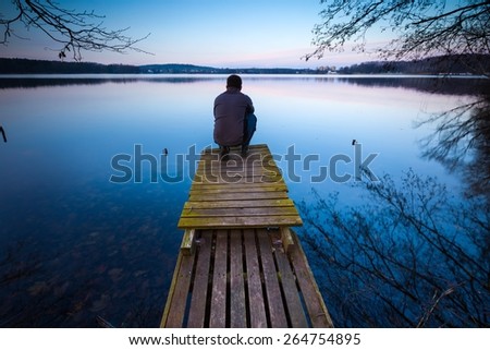 Small pier on lake with man silhouette. Mazury lake district.