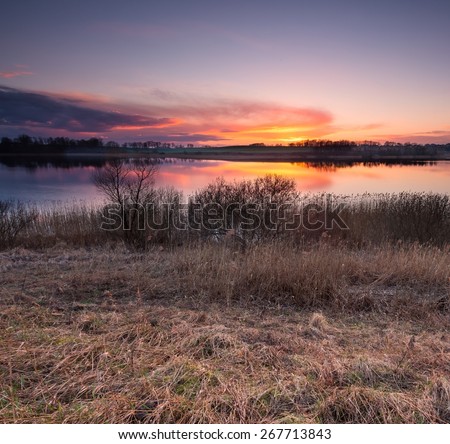Beautiful sunset over calm lake in Mazury lake district. After sunset sky reflecting in water, calm vibrant landscape.