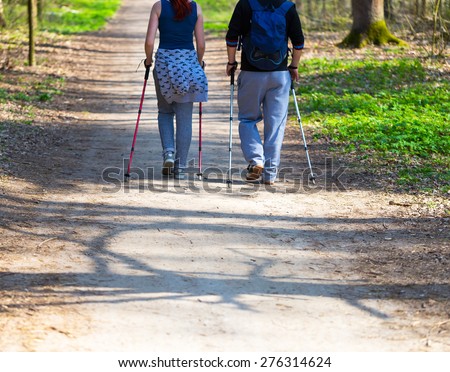 People play sport in forest. Nordic walking couple.