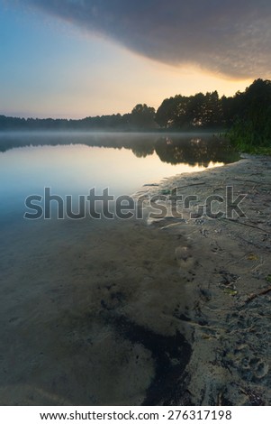 Beautiful sunrise over misty lake. Foggy morning over lake in Mazury lake district, Skanda lake near Olsztyn in Poland.