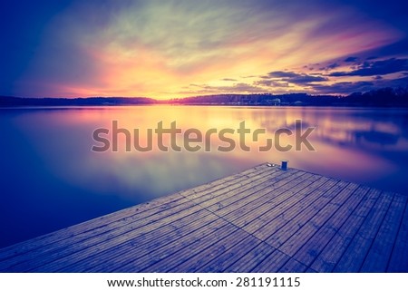 Vintage photo of beautiful sunset over calm lake.