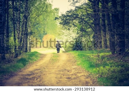 Vintage photo of man walking by forest path. Photo with vintage mood effect