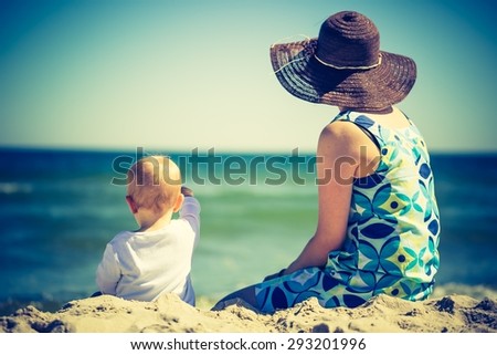 Vintage photo of small child with mother on sea shore. Beautiful landscape with baby and mother photographed from behind
