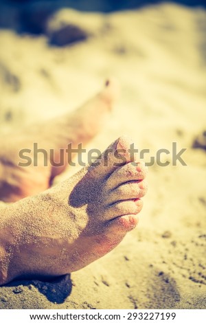 Vintage photo of foot of tanning man lying on beach. Baltic sea shore