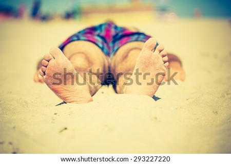 Vintage photo of foot of tanning man lying on beach. Baltic sea shore