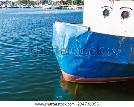 Close up of front side of fisherman ship moored in port. Colorful abstract background of piece of ship