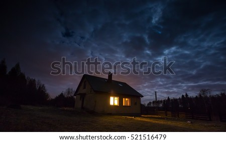 Landscape with house at night under cloudy sky. Spooky landscape with house in night.