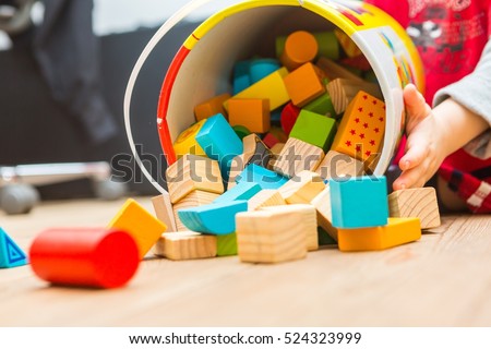 Small boy playing with wooden blocks on floor. Baby toy and child.