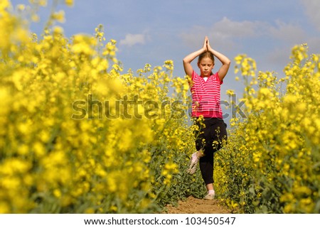 Young girl practicing yoga in the nature trail in the fields