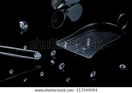 diamond in the tweezers on a black background with other diamonds, and  stone shovel, diamond cut loupe