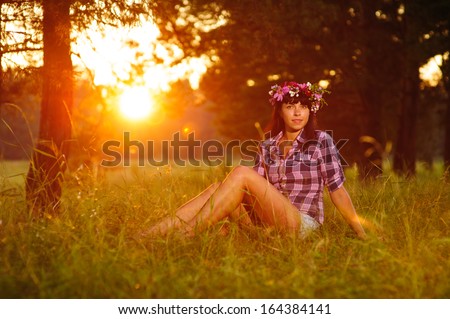 beautiful young woman with a crown of flowers. at sunset in the forest
