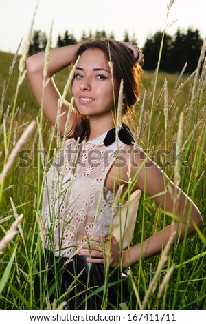 beautiful young woman with earrings made ??of feathers on the field