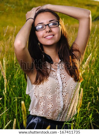 beautiful young woman with earrings made ??of feathers on the field