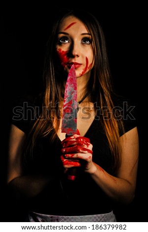 sweet and innocent woman with bloody knife in her hand in the dark