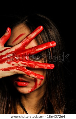 close-up portrait of a young, beautiful and emotional woman covering her face bloody hand