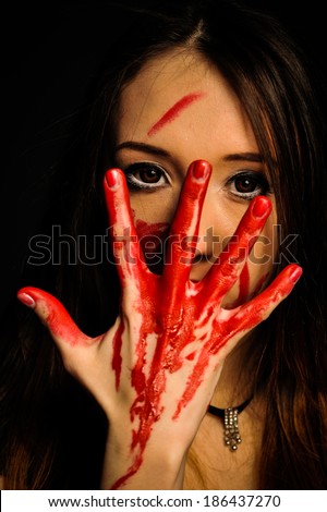 close-up portrait of a young, beautiful and emotional woman covering her face bloody hand