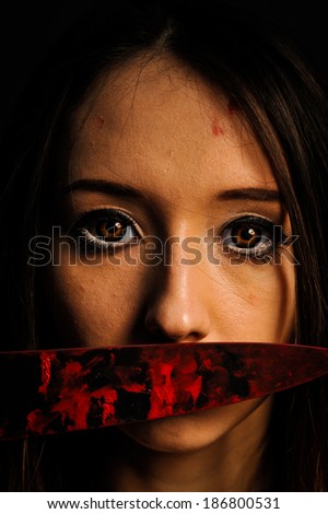 beautiful young woman covers her mouth with bloody knife