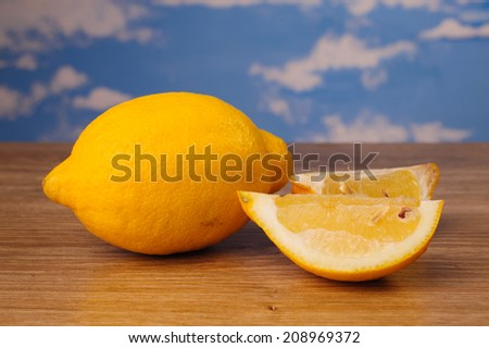 lemon cut into pieces, lying on a wooden board on a background of blue sky