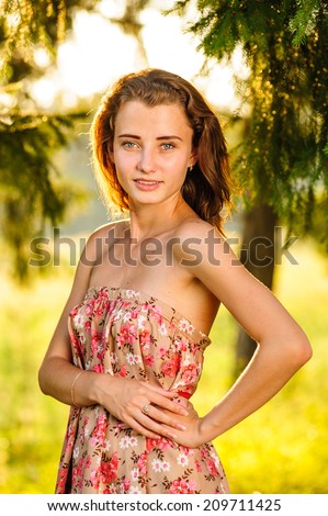 joyful young woman standing on a meadow under a tree