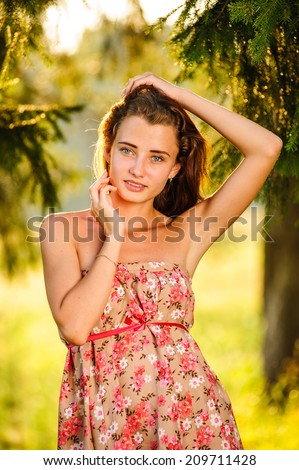 joyful young woman standing on a meadow under a tree