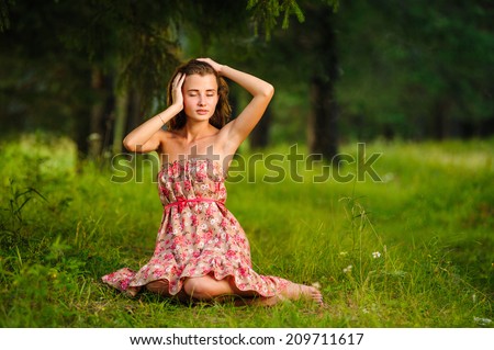 Young happy woman sitting with gtcy, d, in the meadow under a tree