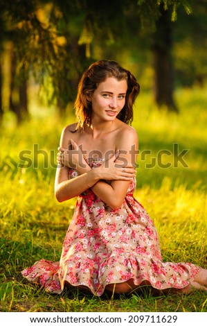 Young happy woman sitting in a meadow under a tree