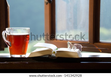 ?up of tea, chamomile flower and an open book on the window. The concept of reading.
