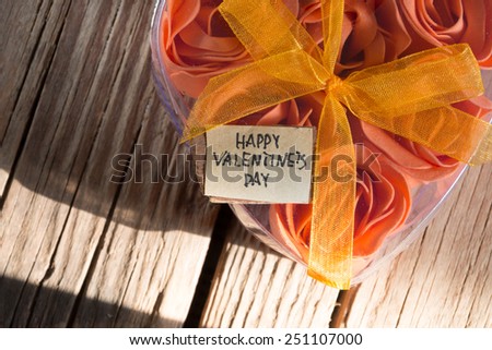 Happy Valentines Day and box with flowers in the shape of heart on the wooden background.