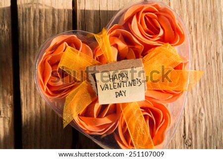 Happy Valentines Day and box with flowers in the shape of heart on the wooden background. Morning sunlight.