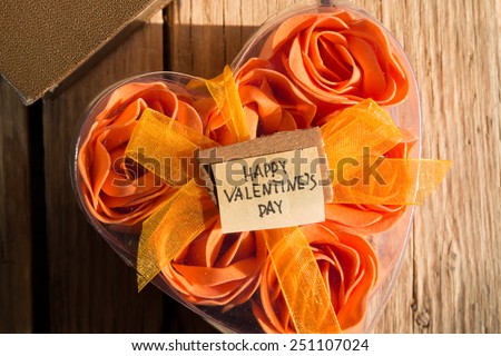 Happy Valentines Day and box with flowers in the shape of heart on the wooden background. Morning sunlight.