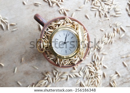 harvest time, gold pocket watch and oat grain on the table