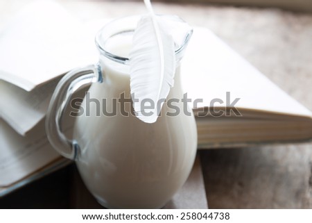 Poetry, poet, writing poems idea. Books, poems, feather and the jug of milk on the table.