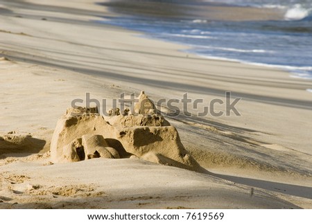 sand castle slowly erodes as the tide begins to come in