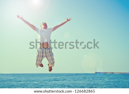 young man jumping with joy at the sea