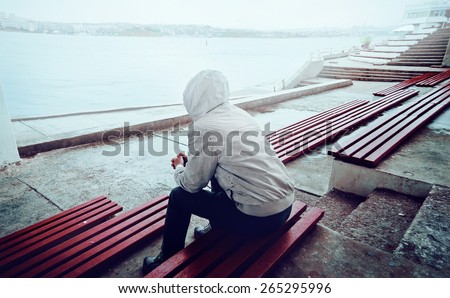 young man sitting on the promenade on a cloudy day
