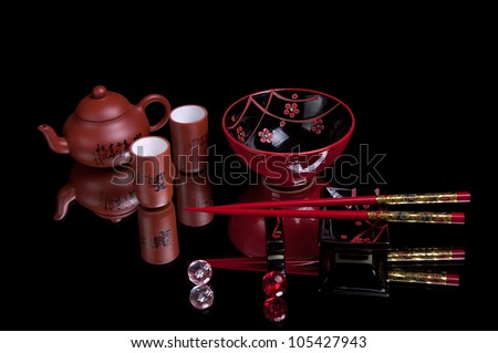 Chinese sticks, red dish, and cups on a black background. Table serving for chinese lunch